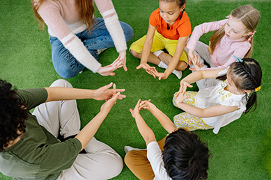 youth and children sitting in a circle